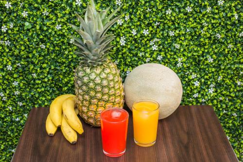 a pineapple and two glasses of juice on a table at Hotel Verona in San Pedro Sula