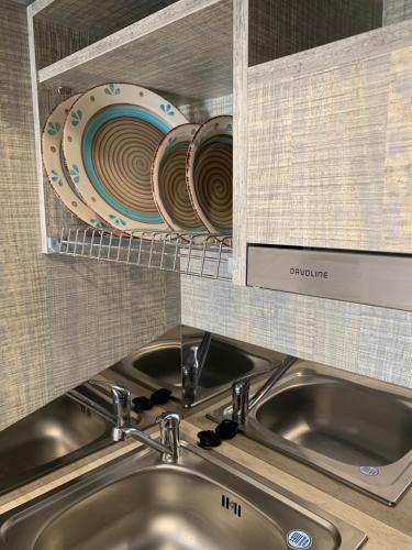 a kitchen sink with plates on a shelf above it at PALS Studios Lindos in Líndos