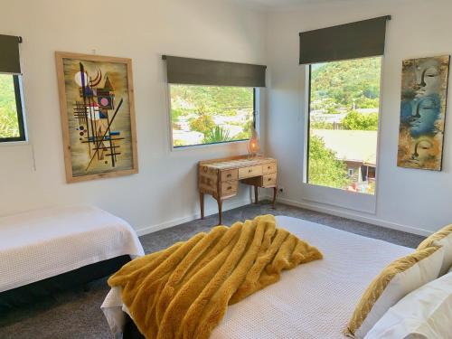 a bedroom with two beds and a desk and two windows at Koru Havenz in Picton