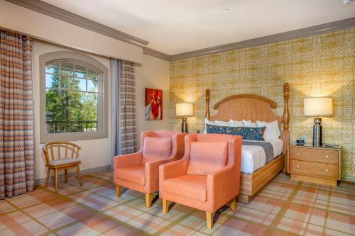a bedroom with a bed and two orange chairs at The Agrarian Hotel; Best Western Signature Collection in Arroyo Grande