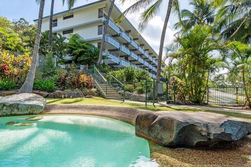 a swimming pool in front of a building with palm trees at Frangipani 103 - Hamilton Island in Hamilton Island