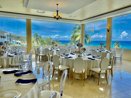 a banquet hall with tables and chairs and a view of the ocean at Hotel El Guajataca in Quebradillas