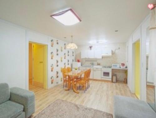 a living room with a table and chairs and a kitchen at Namhae Frankfurt Pension in Namhae