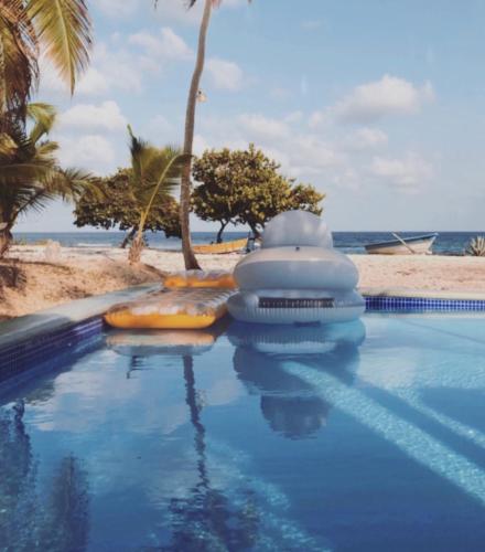 a swimming pool next to a beach with palm trees at Hotel Al Mare in Santa Cruz de Barahona