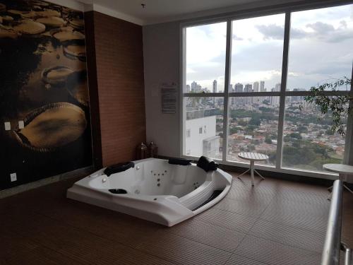 a bath tub in a bathroom with a large window at Flat mobiliado em região nobre de Goiânia in Goiânia