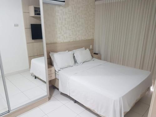 - une petite chambre avec un lit et un miroir dans l'établissement Flat mobiliado em região nobre de Goiânia, à Goiânia