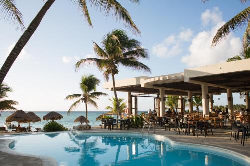 - une piscine dans un complexe avec des palmiers et l'océan dans l'établissement Paamul Hotel, à Palmul