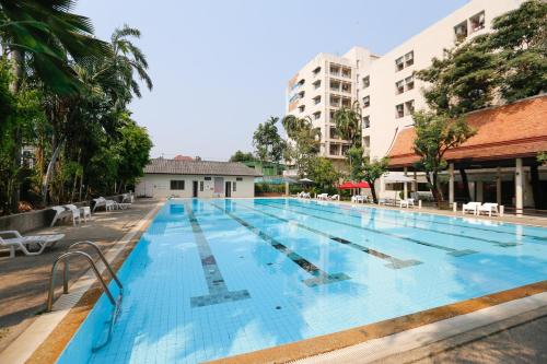 a large swimming pool with chairs and buildings at D-haus Ladprao Residence in Bangkok