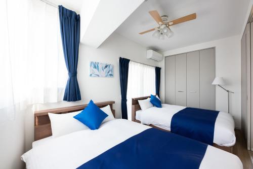 Dos camas en una habitación con azul y blanco. en Grand Inn Canalside, en Fukuoka