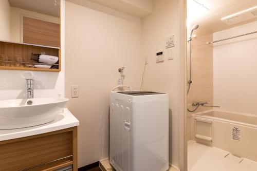 a white bathroom with a sink and a shower at Mr KINJO 万座ビーチ前 in Onna