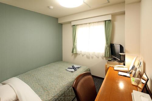 a hotel room with a bed and a desk and a window at Hotel Tateshina in Tokyo