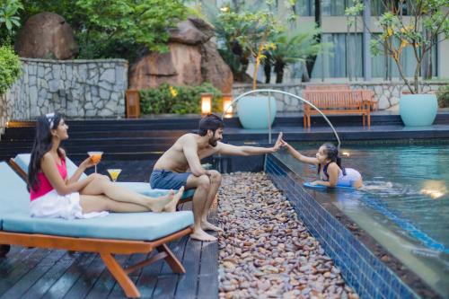 a group of people sitting around a swimming pool at Hyatt Hyderabad Gachibowli in Hyderabad