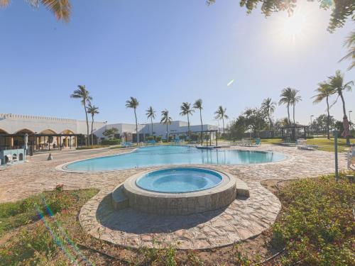 CAPITAL O133 Al Sawadi Beach Resort & Spa في بركاء: مسبح كبير وحوله دائرة حجرية