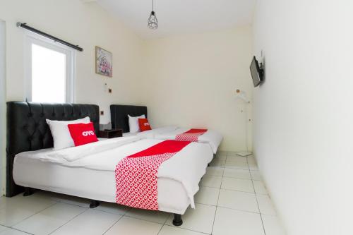 a bedroom with a large bed with red and white pillows at OYO 2975 House Of Mahira Syariah in Ciamis