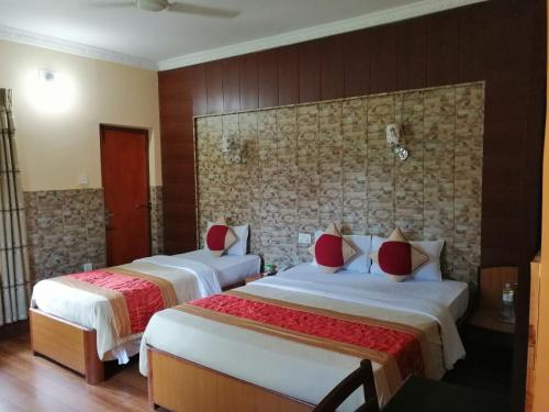 a hotel room with two beds with red pillows at Hotel Wildlife Camp in Sauraha