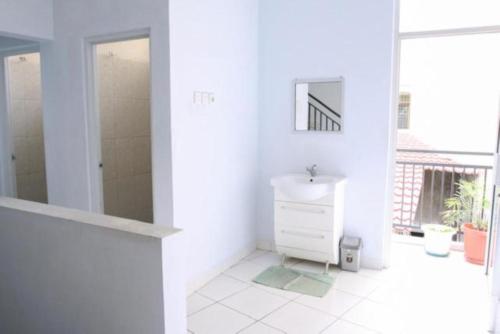 a white bathroom with a sink and a mirror at Rumah Kita in Padang