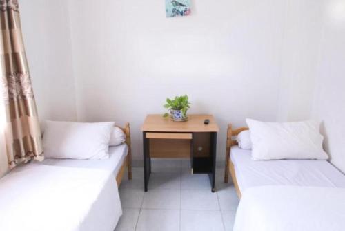 Cette petite chambre comprend deux lits et une table. dans l'établissement Rumah Kita, à Padang