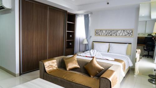 a bedroom with a bed and a couch at Azalea Suites Cikarang by Jayakarta Group in Bekasi
