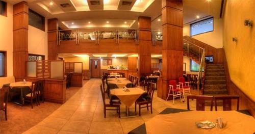 Un restaurante con mesas y sillas y una escalera. en Hotel Deepa Comforts, en Mangalore