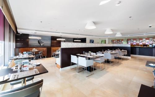 a restaurant with tables and chairs and a bar at Premier Inn Doha Airport in Doha