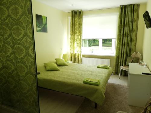 a bedroom with a bed with green sheets and a window at Ravila Manor in Kose
