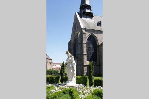 a statue in a garden in front of a church at Studio de charme en centre ville D1 in Douai
