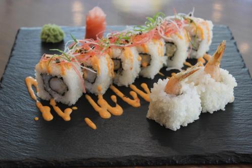 a black plate with sushi and rice on it at Novotel Ahmedabad in Ahmedabad