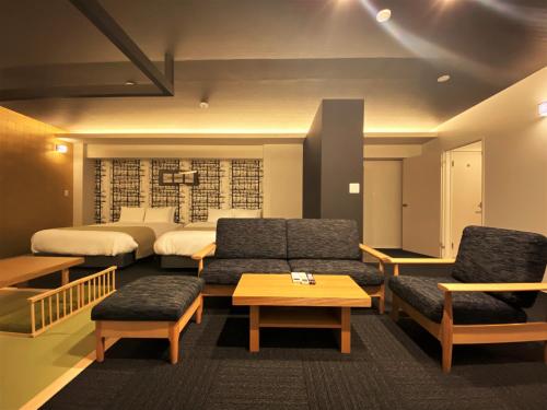 a hotel room with two beds and a couch and a table at Randor Residential Hotel Fukuoka Annex in Fukuoka