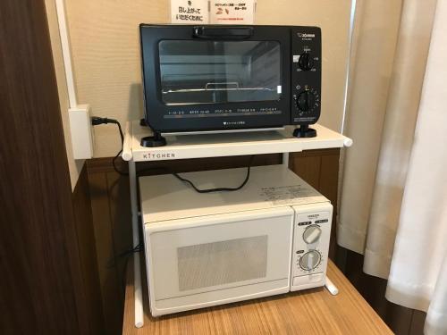 a microwave and a television on a stand with a microwave at Hotel Sunrise21 in Higashihiroshima