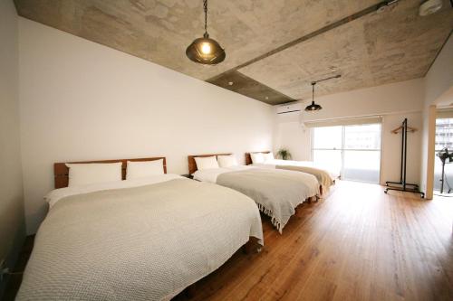 a bedroom with three beds with white sheets at goom Hotel Hakata-Higashihie-Ekimae in Fukuoka