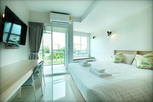 um quarto branco com uma cama e uma varanda em beHOME Phuket em Praia de Nai Yang