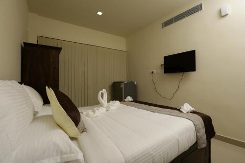 a bedroom with two beds and a flat screen tv at Le Noor in Ernakulam