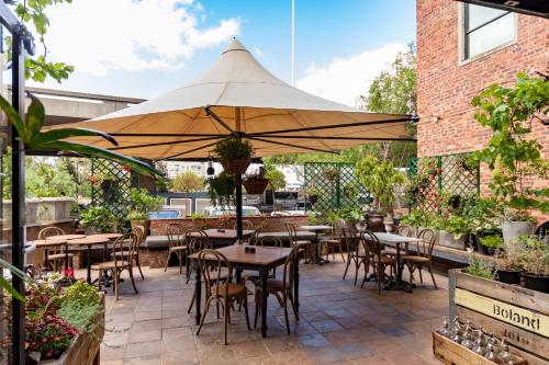 a patio with tables and chairs and an umbrella at Old Foundry Hotel by Ideas Cartel in Cape Town