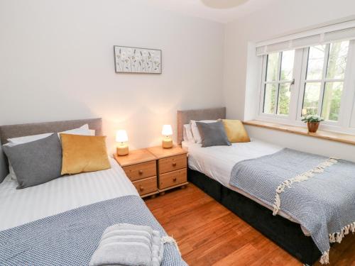 two beds in a bedroom with two windows at Folly Lodge in Barnard Castle
