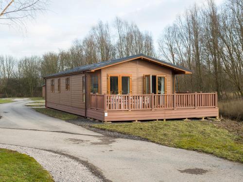 a wooden cabin with a porch on a road at Waternook Lodge in Carnforth
