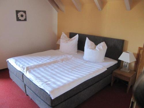 a bedroom with a bed with white sheets and pillows at Pension Sonnengrund in Nonnenhorn