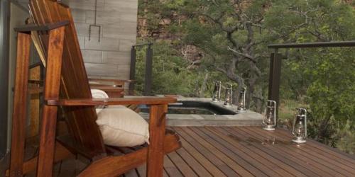 a rocking chair sitting on a wooden deck with a pool at Inzalo Safari Lodge in Welgevonden Game Reserve