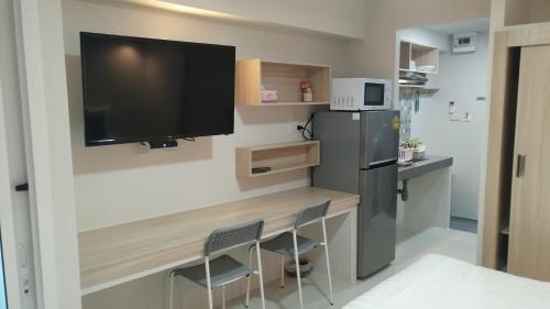 a kitchen with a desk with two chairs and a refrigerator at beHOME Phuket in Nai Yang Beach