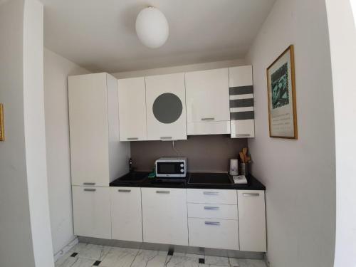eine kleine Küche mit weißen Schränken und einer Mikrowelle in der Unterkunft Il Parco 2 by Quokka 360 - cosy flat with terrace in Lugano