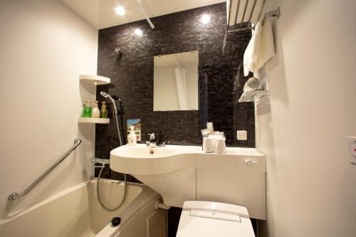 a bathroom with a sink and a toilet and a mirror at JHotelTokyoGEO in Tokyo