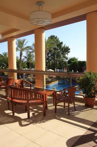 a patio with two benches and a table and a pool at AQI Pegasos Royal in Avsallar