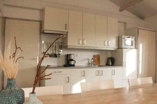 a kitchen with white cabinets and two vases on a table at Vakantie met sauna in Zeeland in Sint Annaland