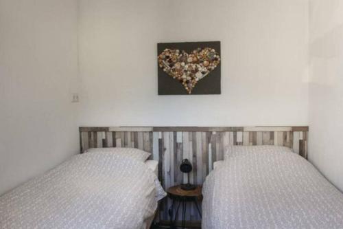 two beds in a bedroom with a heart picture on the wall at Vakantie met sauna in Zeeland in Sint Annaland