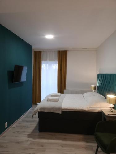 1 dormitorio con 1 cama grande y pared azul en Apartamenty Lawendowy Zakątek 2, en Opole