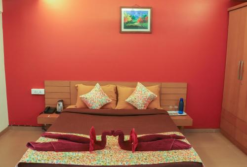a bedroom with a red wall and a bed at Surya Kiran Miramar in Panaji