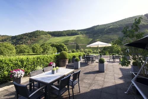 a patio with a table and chairs and a mountain at Weingut & Gästehaus Christoph Clüsserath in Trittenheim