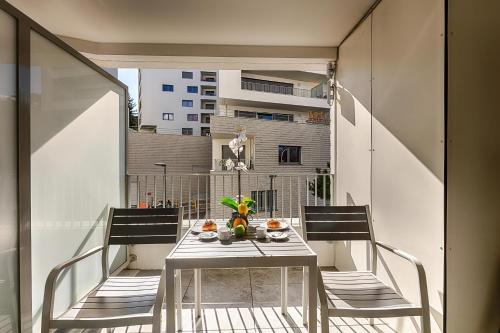 une table et des chaises sur un balcon avec vue sur un immeuble dans l'établissement Appart L'avant Scene Tresums, à Annecy
