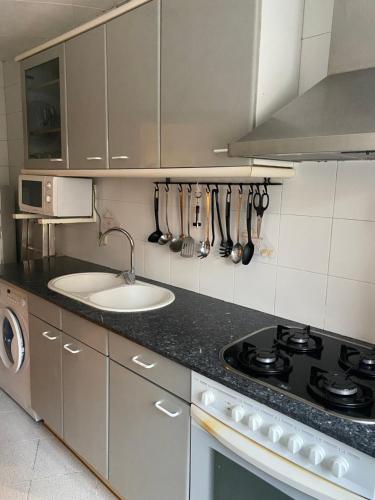 een keuken met een wastafel en een fornuis top oven bij GranVia Fira Apartment in Hospitalet de Llobregat