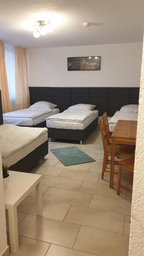 a room with three beds and a table and a table and chairs at Workers-Sleep-Station in Cologne