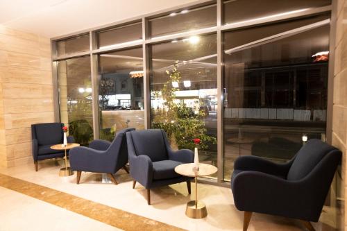 a lobby with chairs and tables and windows at Eva Hotel in Jeddah